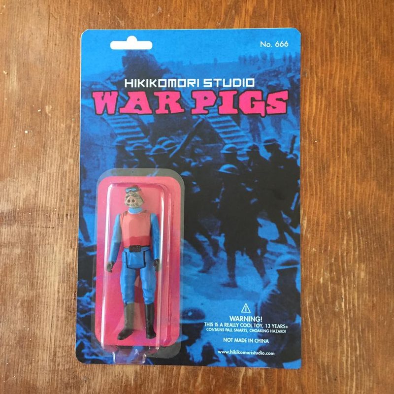 Small plastic action figure with a pig-like face wearing a pink helmet and blue-and-pink uniform, standing on a metal di